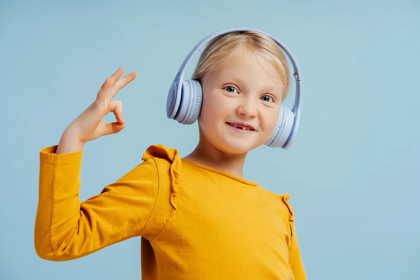 Niña feliz escuchando inglés con audífonos